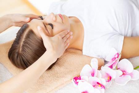 Hands of cosmetologist making manual relaxing rejuvenating facial massage for woman in beauty salon.の写真素材