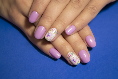 Woman hands with manicure on blue background. Closeup photoの写真素材