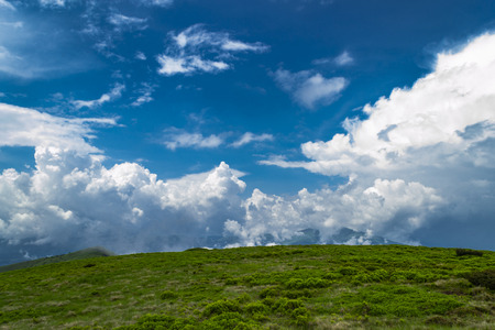 Scenic mountains landscape. White clouds against blue sky with sunrays. Highlands