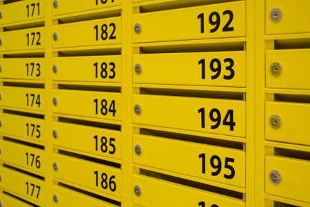 yellow mailboxes in an apartment building. large black numbers on the doorsの写真素材