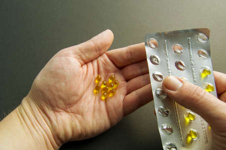 Squeezing pills into the hand. hand holds yellow pills. vitamin d in hand. treatment and prevention...