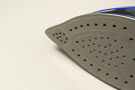 soleplate of a new iron with steam holes. iron lies on a gray background