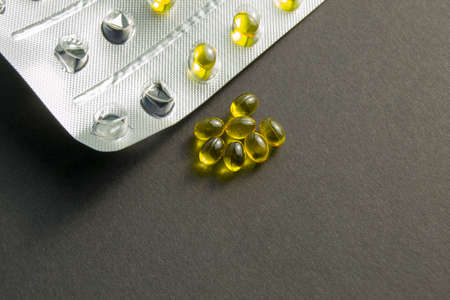Yellow pills on a black background. next to an empty blister. treatment and prevention of diseases....