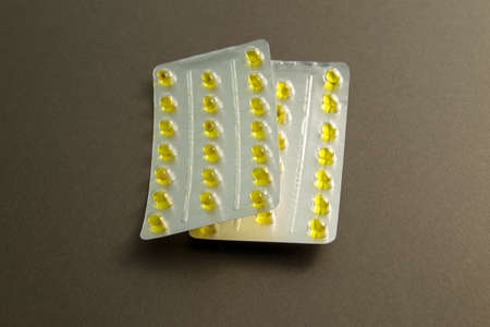yellow pills in a blister pack close up. two plates of pills on a black backgroundの写真素材