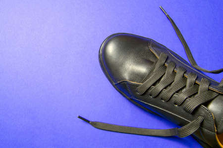 black mens shoes on a blue background. thick wide laces. shoes are at an angle relative to the horizonの写真素材