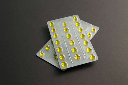 yellow pills in a blister close-up. two plates of pills on a black background. one blister lies on top of the other. increased immunityの写真素材