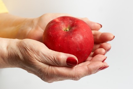 Hand of the elderly lady holding an apple.の写真素材
