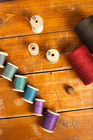 bobbins with thread and needles, striped fabric. Old sewing tools on the old wooden background.の写真素材