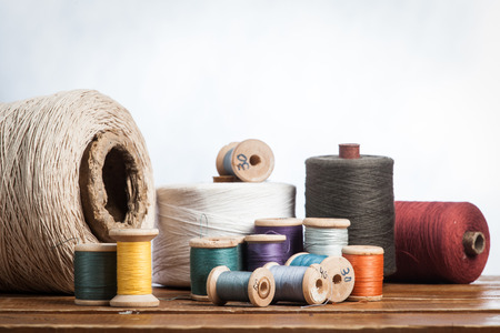 bobbins with thread and needles, striped fabric. Old sewing tools on the old wooden background.の写真素材