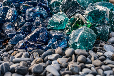 A closeup shot of a pile of broken glass on a pebble beachの写真素材