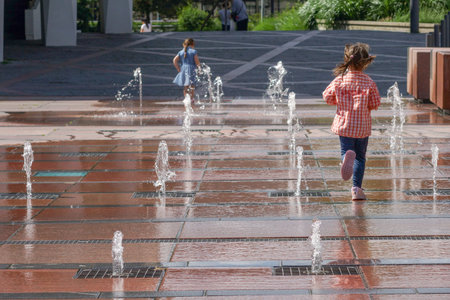 Pforzheim Germany Juni 1, 2018  Child Running Through Fountain Jets, Young Explorer Racing Across City Plaza, Sunlight Glinting On Wet Tile, Water Sprays And Puddles,のeditorial素材