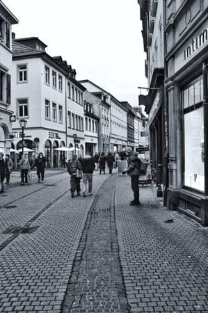 Heidelberg Germany January 24, 2026 Crowded Cobblestone Street With Shoppers And Storefronts, Historic Facades, Streetlamp Reflections Tourist Photographer Framing Shot While Locals Browse Heidelberg Germany January ,のeditorial素材
