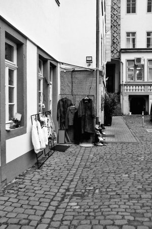 Heidelberg Germany January 24, 2026 Sidewalk Stall With Hanging Garments And Cobblestone Foreground, Vintage Dresses And Coats Displayed Against Shop Wall, Quiet Market Mood Perfect Heidelberg Germany January ,のeditorial素材