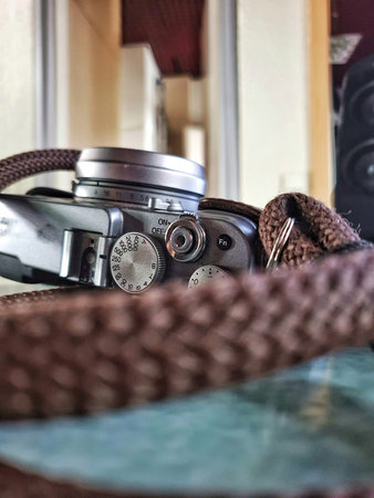 Vintage Camera Closeup On Wooden Table, Metal Dials Leather Strap In Shallow Focus, Warm Light...