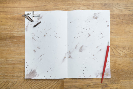 Blots of ink with a pen on a white paper on a wooden table