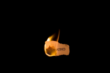 A burning piece of paper with the word hatred on it isolated on black with copy spaceの写真素材