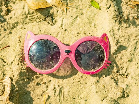 Baby pink sunglasses are in the sand. Girls. Children's games.の写真素材