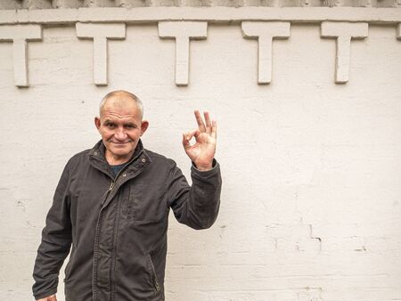 Hand gesture all is well. Ok. A man with a bald head. Gray people.