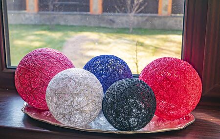 Colored balls of wound thread on a windowsill. Design. Background image. Place for text. Interior.