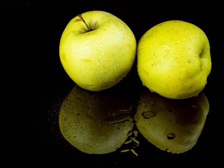 Fruit green apple in drops of water on a black glass background with reflection.の写真素材