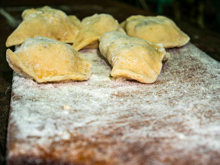 Ukrainian dumplings with dough stuffed on a cutting board. Dumplings. Cooking food. Food photo. Recipe. Shop window. Poster. Template with place for text. Billboard. Home kitchen.の写真素材
