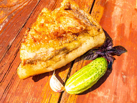 Baked lard with vegetables on a wooden cutting board. Food photo. Ukrainian traditional home cuisine. Recipe. Cooking food. Advertising photo of a shop window. Menu of dishes.の写真素材