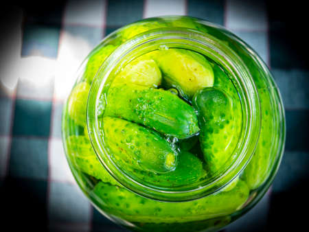 Canned cucumbers in a glass jar on the table. Food photo. Agriculture. Farm. Shop window photo....