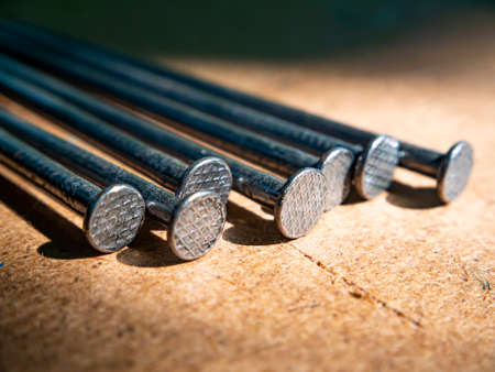 Iron nails on a wooden table macro photo. Nail head. Sharp tip. Joiner's material. Wooden background. Macro photography. Background image. Place for text.の写真素材
