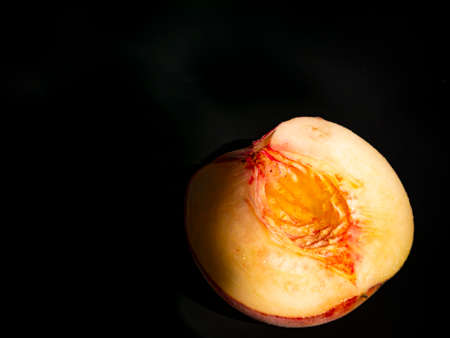 Half peach fruit on a black background. Peach bone. Food photo. Harvesting. Peach juice....