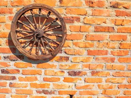 Old wooden wheel on a brick wall.の写真素材