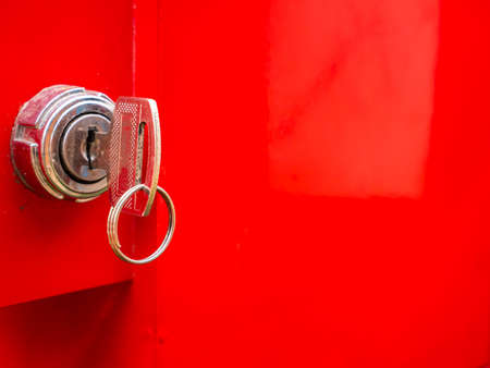 Key in the keyhole on a red background. Car ignition key. Door lock. Open or close the door....
