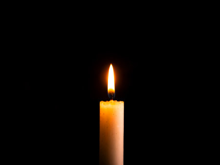 The flame of a burning wax candle in the dark. Flame of wax candle fire. Fire in the dark. Day of Remembrance. A minute of silence. Funeral services. Tribulation on Memorial Day. Place for text.の写真素材