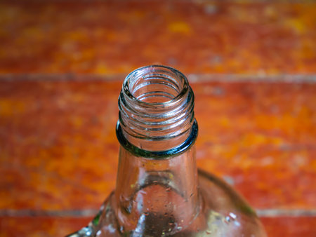 Glass bottle for vodka with a handle on a wooden background. Neck of a glass bottle. Alcohol. Glassware for alcohol. Bad habits. Alcoholism. Background image. Container with a handle.の写真素材