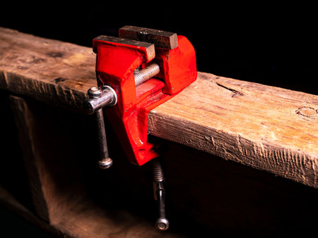 Locksmiths tool metal vise fixed on a wooden table.の写真素材