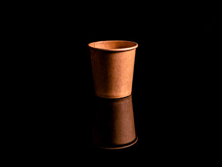 Disposable cardboard coffee cups on a black background. Cardboard colored cups. Disposable tableware. Coffee drinks. Paper dishes for drinks. Hot tea. Black background. Darkness.の写真素材