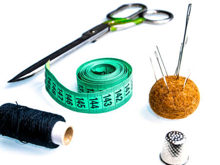 Measuring meter and sewing accessories on a white background. Yardstick. Centimeter or Inch. Needles and threads. Tailors scissors. Seamstress tool. Clothing sewing and repair. Clothing size.の写真素材