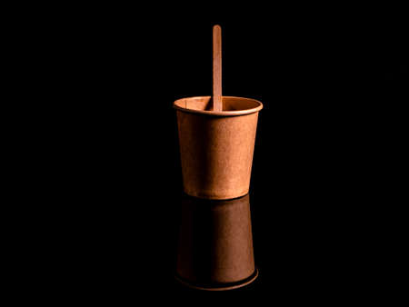 Disposable cardboard coffee cups on a black background. Cardboard colored cups. Disposable tableware. Coffee drinks. Paper dishes for drinks. Hot tea. Black background. Darkness.の写真素材