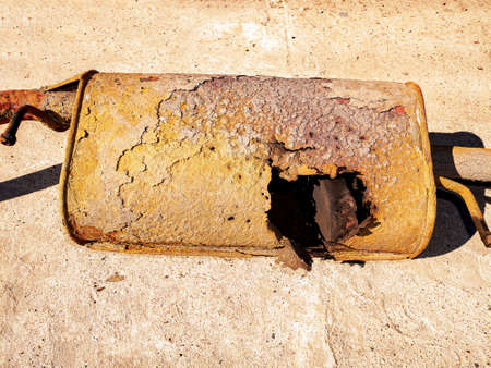 Old rusty car muffler with a burnt hole. Exhaust system of the car. Auto muffler. Vehicle. Vehicle...