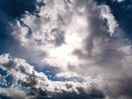Sun rays shining through the clouds on the blue sky.