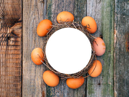A circle of chicken eggs on a wooden table.の写真素材