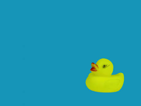 Children's toy bird yellow duckling on a blue background of water. Duck bird. Kids toys. Blue water color background. Little ducklings. An object of entertainment for kids.の写真素材