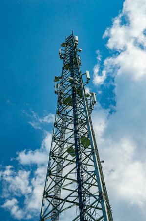 A tower for mobile communication antennas against a blue sky with white clouds. Mobile operator antennas. Radio communication tower. Internet and telephony. internet business. The beauty.の写真素材