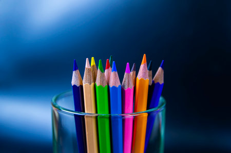 Colored pencils for drawing in a glass on a black background. Colored pencils for drawing. education and art. artist's tool. stationery. glassware. beautiful colors. creative business.の写真素材