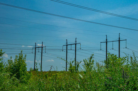 Tower with high-voltage energy transmission wires against the blue sky.