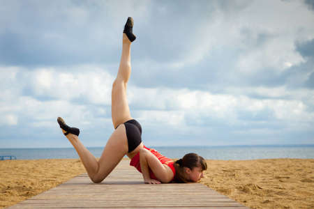Young woman doing stretching on a beach 