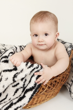 Beautiful baby portrait with cute facial expression sitting in a basket の写真素材