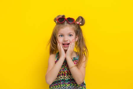 Cute little girl in sun glasses on the yellow background in the studio.の写真素材