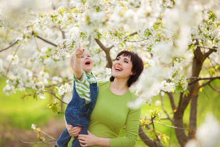 Happy woman and child in the blooming spring garden.