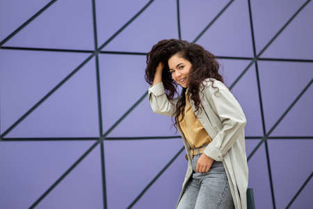 Smiling young stylish woman with curly hair