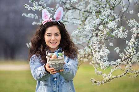 Happy young woman wearing bunny ears holding colorful easter eggs